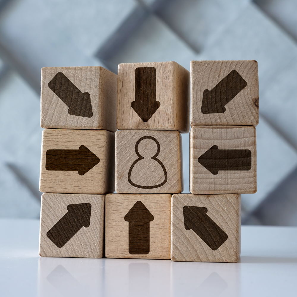 naturally colored wooden figures on wooden planks in line behind a red wooded figure who uses a red plank to get past the gap in planks